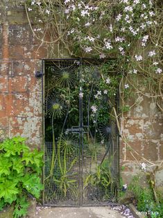 an iron gate surrounded by plants and flowers