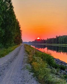 the sun is setting over a river with trees on both sides