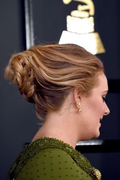 a woman with her hair in a low bun at the red carpet wearing a green dress