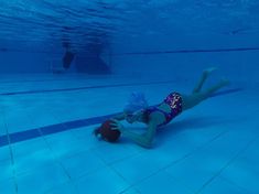 a woman in a swim suit is playing with a ball under the water