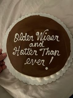 a person holding a cake with the words older wiser and faster than ever on it