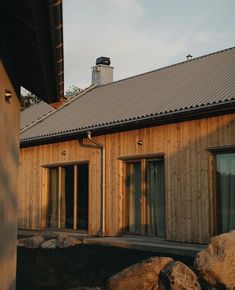 a house with wooden siding and windows next to rocks