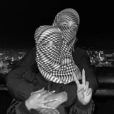 two women with headscarves are standing in front of a cityscape at night