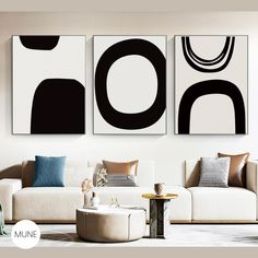 three black and white paintings hang on the wall in a living room with modern furniture