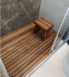 a wooden bench sitting on top of a bathroom floor next to a walk in shower