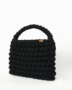 A unique handmade black bag with an impressive weave thanks to its thick yarn. 100% recycled cotton thread and ecological leather tag with the CrosiS brand were used. The woven strap gives the bag a surprising simplicity and harmony. The interior is made of high quality upholstery. A special bag for the woman looking for minimal style and comfort. This bag will become the favorite part of your wardrobe as with its impressive and simple knitting you will be able to easily combine it with many out Simple Knitting, Purse Storage, Handmade Crochet Bags, Leather Tag, Black Handbag, Thick Yarn, Top Handle Bags, Crochet Bag Pattern, Easy Knitting