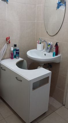 a bathroom with a sink, mirror and toilet paper dispenser in it