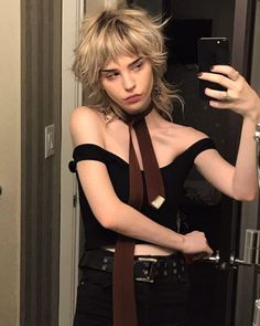 a woman taking a selfie in the mirror wearing a neck tie and black top