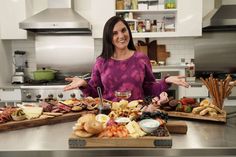 a woman standing in front of two trays of food on a kitchen counter top