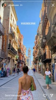 a woman is walking down the street with her back turned to the camera and she's wearing a colorful dress