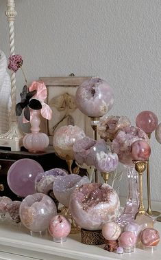 an assortment of pink and white vases sitting on top of a dresser next to a mirror