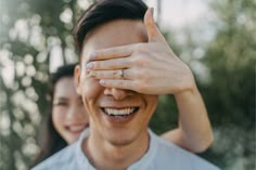 a man and woman are smiling with their hands on the forehead