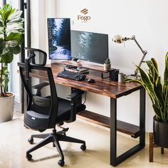 a desk with a computer, keyboard and plant on it next to a large window