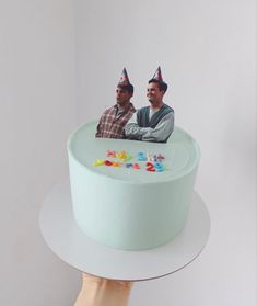 two men sitting on top of a birthday cake