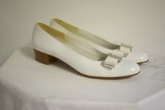 "Vintage 1980s/90s white leather flat heels with a bow on the toes. Made by Salvatore Ferragamo in Italy. The style is Vara. Marked a size 7 1/2 AAAA. They measure 9 5/8\" long inside from toe to heel and 2 3/4\" wide. The stacked wooden heel is 1 1/2\" tall. In fair to good condition, with some wear to the soles, some yellow/rust-like discoloration on the bow and metal piece on one shoe, and a few light spots. They have their original box. ---> If you need an order shipped by a particular da Heels With A Bow, Chrissy Cunningham, 1980s Shoes, 80s Shoes, Steampunk Boots, Hogwarts Dr, Flat Heels, Shoe Wardrobe, Kawaii Shoes