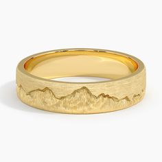 a yellow gold wedding band with mountains in the middle and a mountain range on it