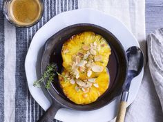 a pan with some food in it on a plate next to a glass of orange juice