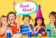 several children sitting at a table with birthday hats on and one holding a sign that says kack knack