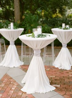 the tables are set up with white linens and greenery on them for an outdoor wedding