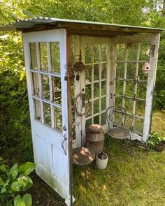 an old outhouse is sitting in the grass with buckets and other things around it