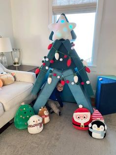 a child is playing in front of a christmas tree made out of stuffed animals and lights