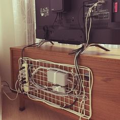 a tv sitting on top of a wooden table next to a wall with wires running through it