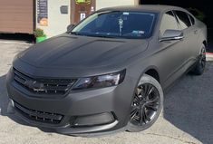 a gray car parked in front of a garage