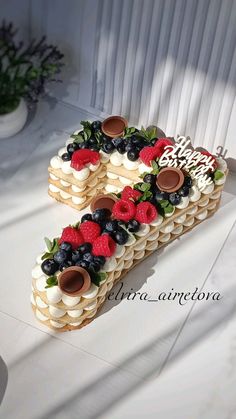 a cake shaped like the number five with berries and strawberries on top is sitting on a table