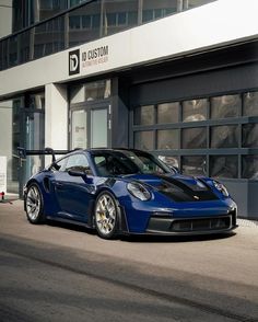 a blue sports car parked in front of a building