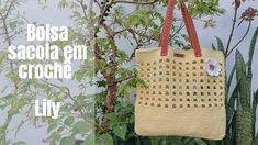 a crocheted bag hanging from a tree next to a wall with plants in the background