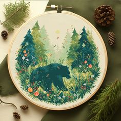 a cross stitch bear in the woods surrounded by pine cones and evergreen needles, on a green background