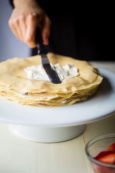 a person cutting up some food on top of a white plate