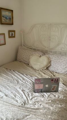 an open laptop computer sitting on top of a bed next to a pillow and pictures