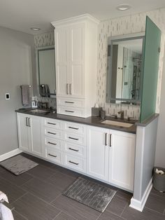 a bathroom with two sinks and mirrors on the wall next to a rug in front of it