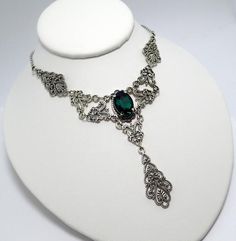 This is a new handmade necklace. It is made with antiqued silver plated filigrees, accented with a high quality EMERALD GREEN glass rhinestone. Decorated portion is 6" wide and 3 1/4" tall in the center. Necklace is adjustable 15-18" with a lobster clasp and chain extender. If you would like a different length, please send us a message. Antique Silver Victorian Metal Necklace, Victorian Antique Silver Necklace, Victorian Antique Silver Metal Necklace, Gothic Filigree Necklace For Wedding, Gothic Metal Necklace With Intricate Design, Victorian Filigree Metal Necklaces, Gothic Antique Silver Jewelry With Intricate Design, Gothic Wedding Necklace With Filigree Detail, Gothic Filigree Wedding Necklace