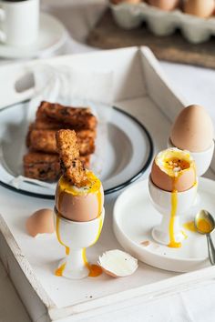 two eggs with mustard drizzled over them on a plate next to other food