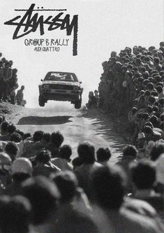 a black and white photo of a group of people watching a car go down the road