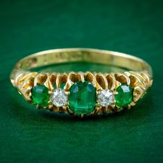 A gorgeous antique Victorian five stone ring set with three deep green step cut emeralds with two twinkling old mine cut diamonds in between. The centre emerald weighs approx. 0.40ct, with 0.10ct outer stones and 0.06ct diamonds.  Emerald is the birthstone of May. The Romans considered it to be the sacred stone of the goddess Venus and was said to preserve love and provide hope. Its natural green colouring also makes it a stone of springtime and is associated with eternal love and faithfulness. Antique Green Oval Diamond Ring, Green Emerald Ring With Rose Cut Diamonds For Anniversary, Anniversary Green Emerald Ring With Rose Cut Diamonds, Vintage Green Emerald Ring With Rose Cut Diamonds, Classic Green Emerald Ring With Single Cut Diamonds, Antique Green Emerald Cut Ring, Vintage Green Emerald Diamond Ring, Antique Green Emerald Cut Emerald Ring, Vintage Emerald Diamond Ring In Green