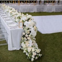 the table is set with white flowers and place settings for guests to sit down at