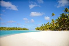 the beach is surrounded by palm trees and clear blue water in front of an island