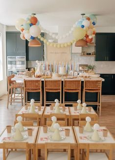 a room filled with lots of tables covered in white tablecloths and balloons hanging from the ceiling