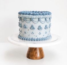 a blue and white cake sitting on top of a wooden stand