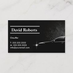 a black and white business card with a car in the background on a marble surface