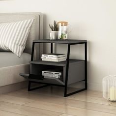 a black end table sitting on top of a hard wood floor next to a bed