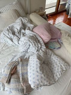 an unmade bed with blankets and pillows on it