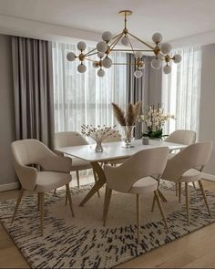 a dining room table with white chairs and a chandelier