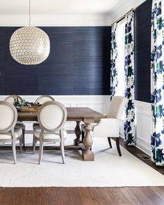 a dining room with blue walls and white chairs