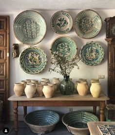 a table topped with bowls and vases next to a wall mounted on the wall