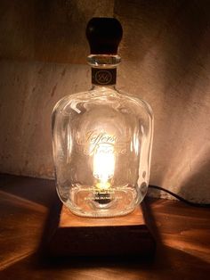 a glass bottle sitting on top of a wooden table next to a lightbulb