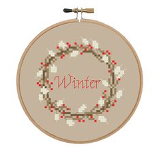 a cross - stitch wreath with the word winter written in red and white on it